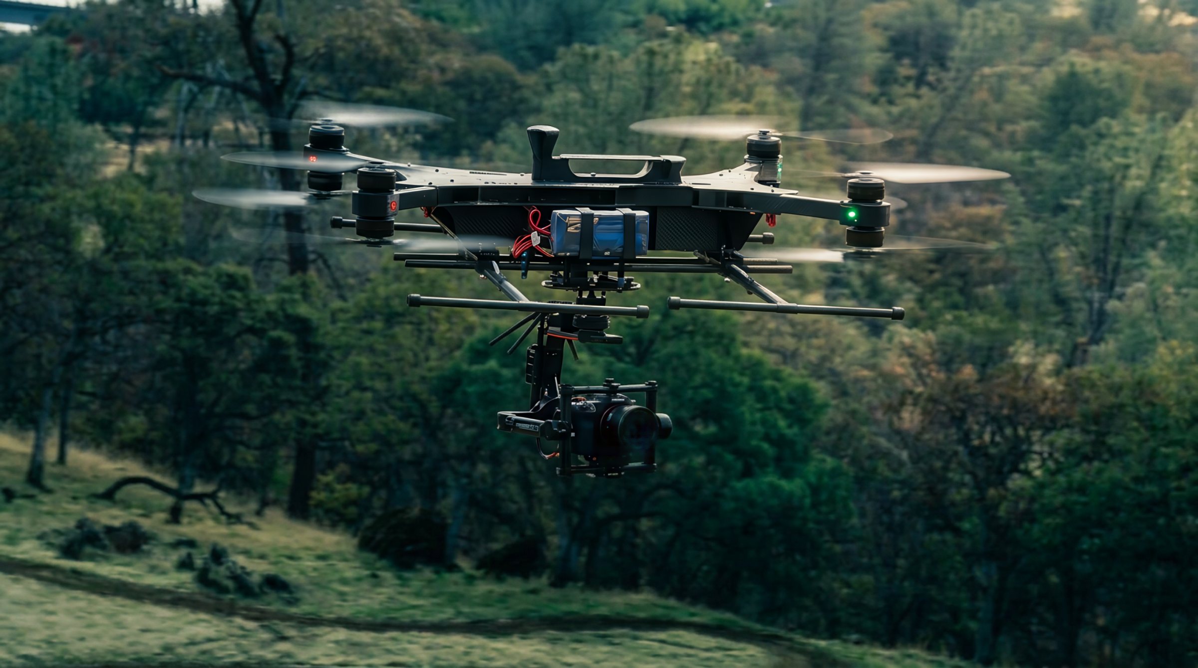 Spy on station above wooded terrain, gimbaled sensor slung beneath the airframe